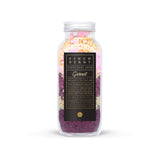 Glass bottle canister with metal lid filled with garnet purple, pink, and gold bath salt with a black finchberry label