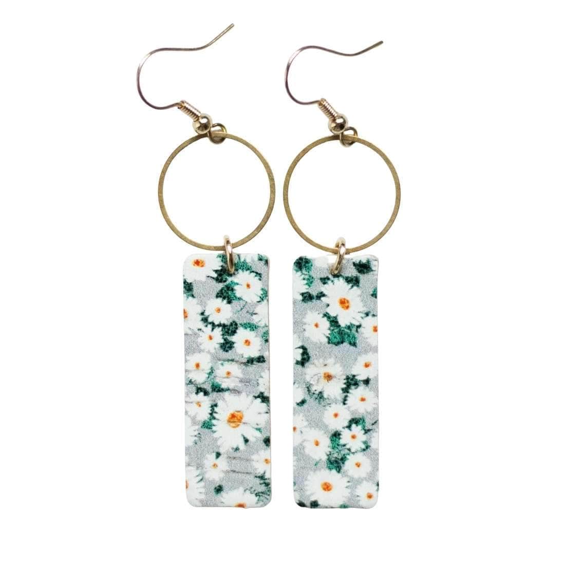 Sela Design Meadow Mia Earrings with white daily floral pattern on rectangular leather pieces adorned with circle brass charm at top of earring
