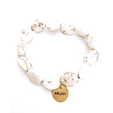Stone, almost marble like white beads and brass beljoy charm bracelet over white backdrop