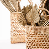Multiple straw baskets with handles filled with paper fans that look like greenery