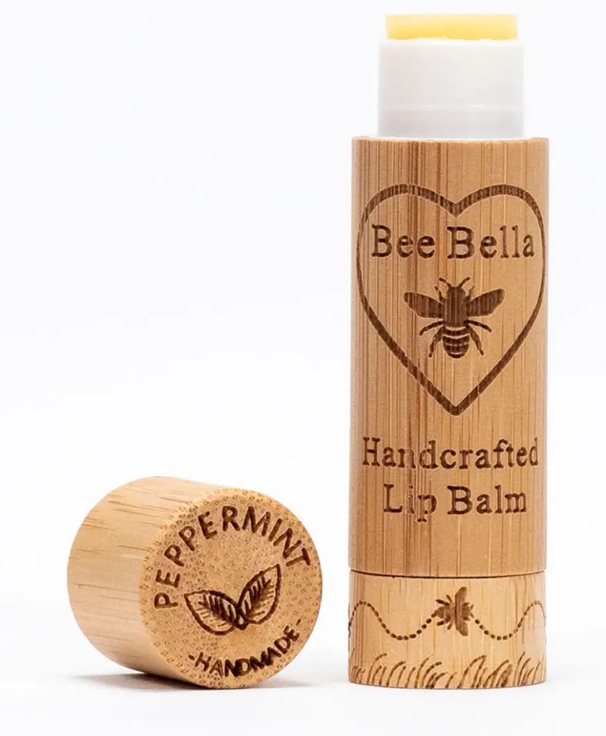 Peppermint Lip Balm with wooden cap set down to the left of the photo, and upright lip balm embossed with logo on the right.