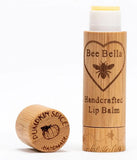 Pumpkin Spice Lip Balm with wooden cap set down to the left of the photo, and upright lip balm embossed with logo on the right.