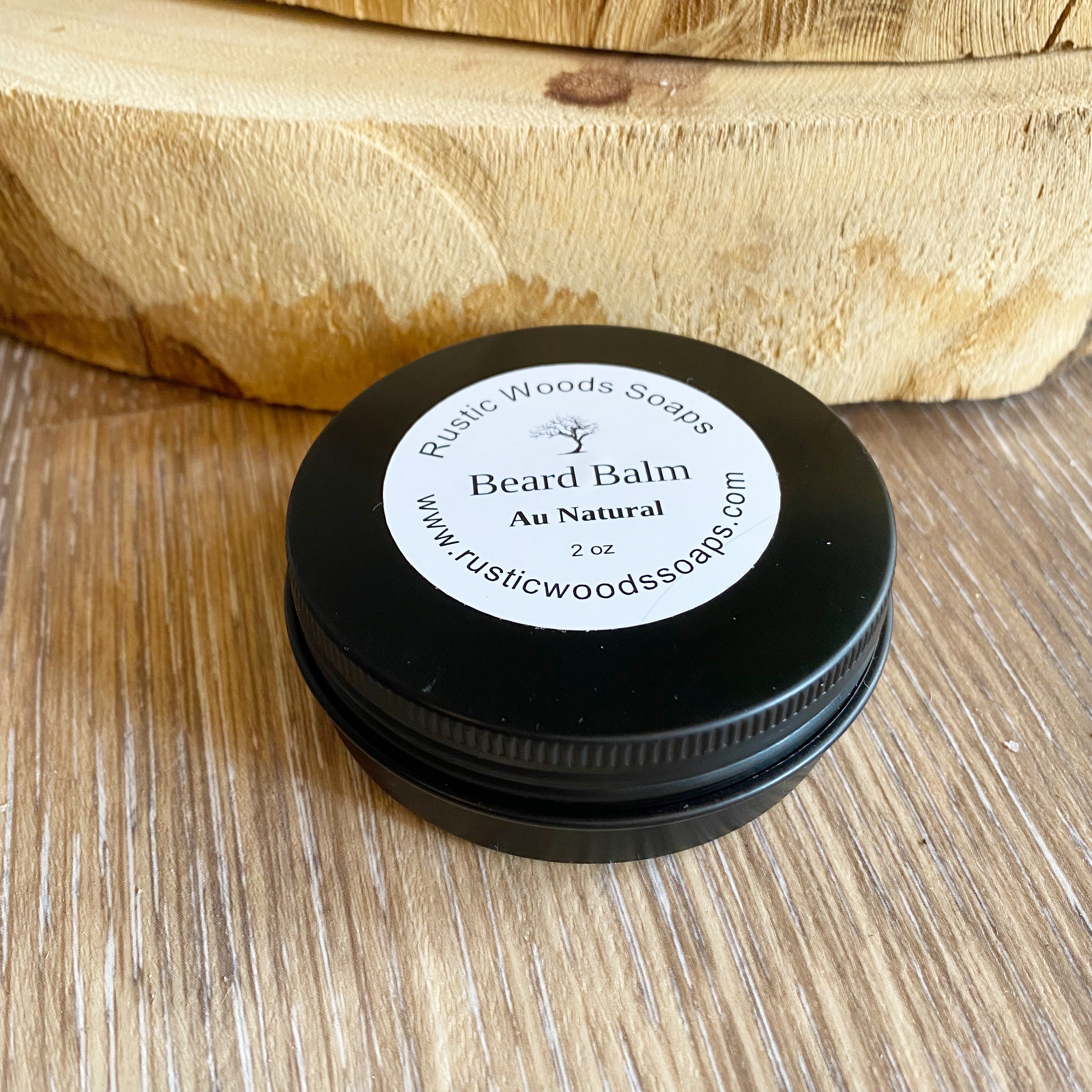 Black canister jar with white rustic woods soaps au natural beard balm label sits on wood surface